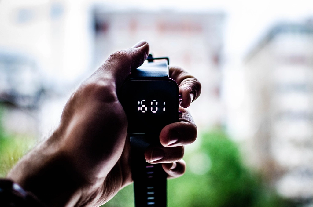 person's hand holding digital watch